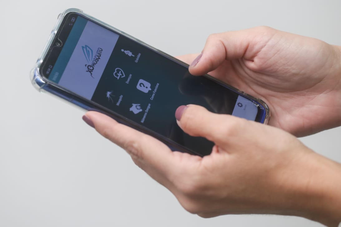 mãos segurando smartphone com aplicativo Xô, Mosquito na tela